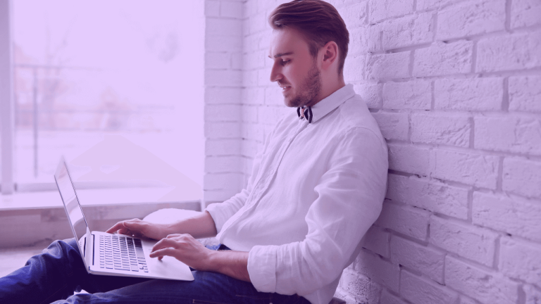 A imagem mostra um homem sentado com um notebook no colo, estudando para sua transição de carreira para Produto.