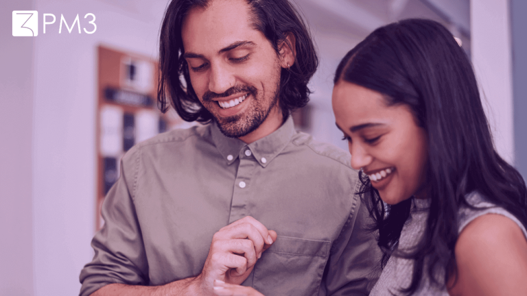 A imagem mostra um homem e uma mulher sorrindo e olhando para um tablet, fazendo a análise do comportamento do consumidor par