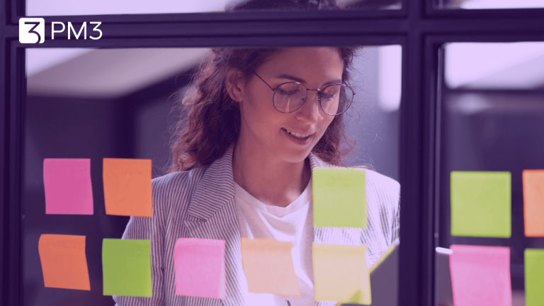 A imagem mostra uma mulher consultando tablet em frente a um quadro com post-its coloridos. A foto ilustra uma profissional u